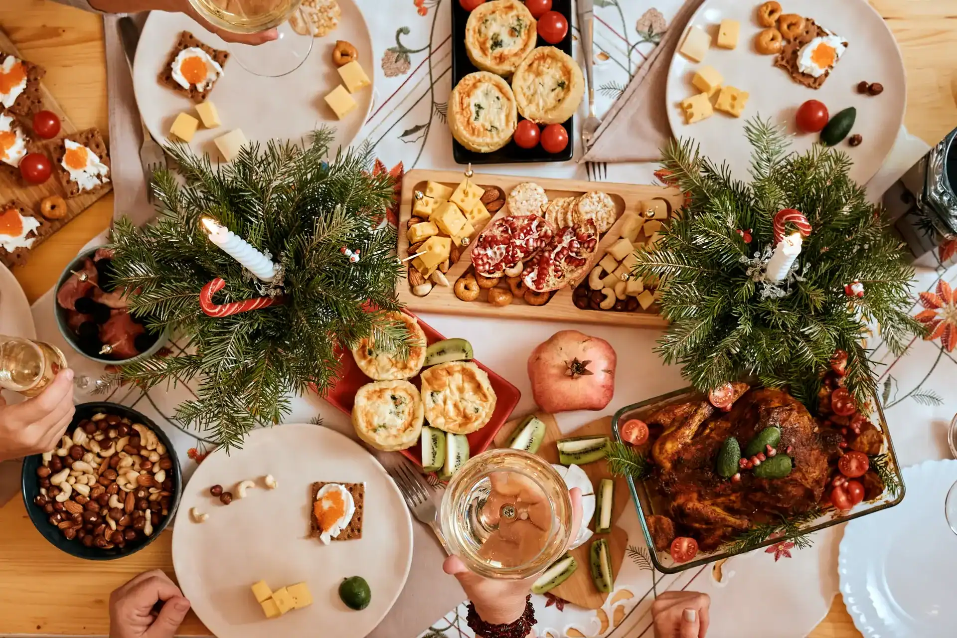 Weihnachtlich gedeckter Brunch-Tisch mit Braten, Vorspeisen-Häppchen und Nussschalen zwischen Deko aus Tannenzweigen