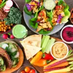 Große Auswahl an veganen und vegetarischen Speisen auf rustikalem Holztisch.
