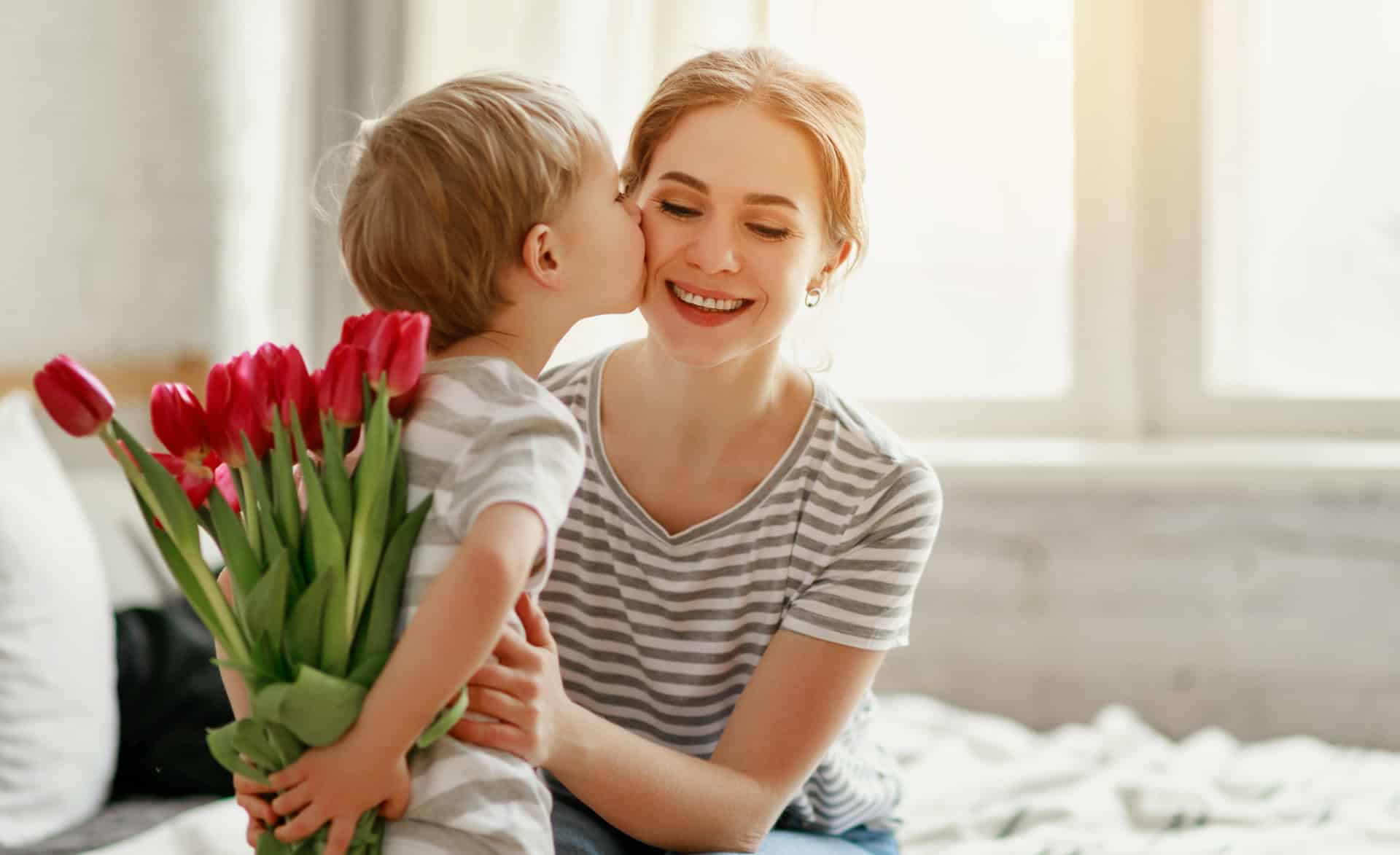 Sohn gratuliert Mutter zum Feiertag und schenkt Blumen